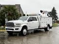 A white 2024 RAM 5500 truck with a utility body and mounted equipment on the bed is parked on a wet surface