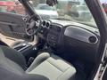 Interior of a 2005 Chrysler PT Cruiser featuring a gray dashboard with several controls and buttons a gear shift and fabric seats
