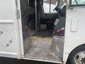Interior view of a 2012 Ford Econoline showing driver's seat and passenger seat with visible step and fire extinguisher on the floor