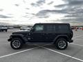 A black 2019 Jeep Wrangler parked in a lot with a four-door configuration and rugged design