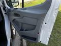 The interior door panel of a 2017 Ford Transit featuring a gray handle and a storage compartment