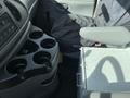 A 2008 Ford Econoline interior featuring a console with multiple cup holders and a metal storage box next to the driver's seat