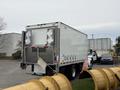 White 2017 Kenworth T370 box truck with a metal rear door and reflective markings parked next to a large yellow pipe