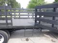 A 2001 Ford F-650 flatbed truck with a metal railing on the sides and a flat wooden cargo area