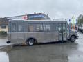 A 2017 Chevrolet Express bus with a metallic body and large windows parked on a roadway