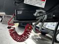 A close-up of a breakaway switch with a coiled red wire and a metal hook attached to a recreational vehicle's hitch