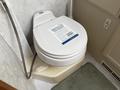 A toilet inside a 2000 Ford Motorhome with a promotional flyer on the seat