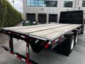 A 2011 International 4400 flatbed truck with a wooden bed and reflective stripes on the back