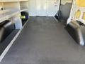 The image shows the interior of a 2016 Ford Transit van featuring a flat black floor and storage compartments along the sides
