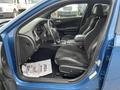 Interior view of a blue 2022 Dodge Charger showing the front seats dashboard and console with black upholstery and a floor mat that has a thank you message