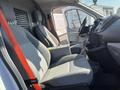 A 2016 Ford Transit interior showing two gray seats with a center console and steering wheel visible