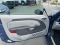 A 2007 Chrysler PT Cruiser with a partially open driver's door showing a light gray interior door panel and a small round mirror