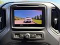 A 2022 GMC Sierra 1500 rearview camera display showing a vehicle ahead on a road with guiding lines for parking assistance