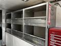 A 2006 GMC C5000 truck with an empty cargo area featuring metal shelving units and a red tool chest against the wall