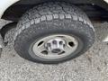 A close-up of the wheel of a 2014 GMC Savana featuring a sturdy tire tread pattern and a silver alloy rim with the GMC logo in the center