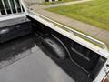 A 2017 Ford F-350 SD truck bed featuring a textured black floor with a storage compartment and a wheel well visible on one side