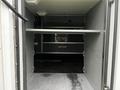 Interior storage space of a 2016 Chevrolet Express showing a gray shelving unit with metal supports and a flat floor