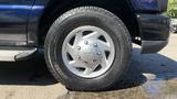 Close-up of a silver alloy wheel on a 2013 Ford Econoline with a black tire featuring tread patterns