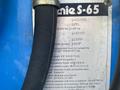 A blue 1997 Genie S-65 4X4 lift with specifications label attached detailing weight capacity, platform height, and other operating parameters