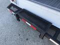 A 2012 Ford Econoline E-450 with a metal step and a textured surface at the rear bumper with red and white reflective strips