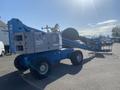 A blue 1997 Genie S-65 4X4 aerial lift with large rubber tires and a boom arm extended ready for operation