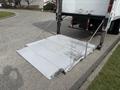 A steel loading ramp is extended from the back of a 2017 Hino 338 truck secured with chains