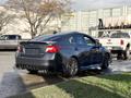 A 2021 Subaru WRX in dark color parked at an angle showing its sleek design and sporty features including a rear spoiler and dual exhaust pipes