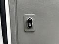 A close-up view of the door lock button on a 2008 Ford Econoline van with a textured gray surface and a black interior button