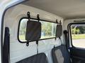 Interior view of a 2008 Suzuki Carry showcases two gray fabric seats and a back window with a mesh screen secured by black straps