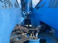 Close-up of a blue 1997 Genie S-65 4X4 boom lift showing its hydraulic hoses and machinery components
