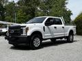 A white 2017 Ford F-250 Super Duty truck with a black front grille and chrome wheels parked on gravel