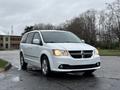 A white 2017 Dodge Grand Caravan parked with its headlights on and a sleek design featuring a black grille and chrome accents