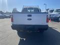 A 2014 Ford F-250 Super Duty truck viewed from the rear with a white exterior and a metal bed rack.