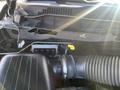 Close-up of the engine compartment of a 2011 RAM 1500 showing parts such as the air intake and various components with a yellow dipstick visible