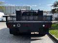 A black 2016 Ford F-550 truck with a flatbed and a mesh rear guard visible from the back