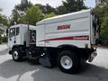 A 2012 Autocar Xpert street sweeper with a white and red body a mounted broom on the front and visible exhaust and side mirrors