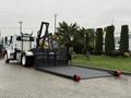 A 2019 Freightliner M2 truck with a flatbed attachment featuring a ramp and hydraulic lift system for loading cargo