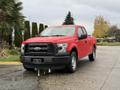 A red 2015 Ford F-150 pickup truck parked with a black front grille and silver alloy wheels