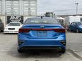 A blue 2021 Kia Forte seen from the rear with sleek taillights and a sporty design