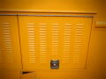 A bright yellow panel with horizontal ventilation slits and a rectangular lock on a 2008 Freightliner MT45 Chassis