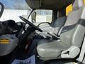 Interior cabin of a 2017 Hino 155 truck featuring a driver's seat and a passenger seat both with gray upholstery and a dashboard with controls and a fire extinguisher visible