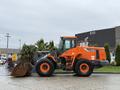 A 2018 Doosan DL300-5 wheel loader with an orange and black exterior equipped with a large front bucket for lifting and moving heavy materials