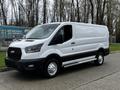 A 2023 Ford Transit cargo van in white with a black front grille and silver wheels positioned at an angle