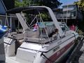 A 1991 Larson Mirado boat with a white and red design featuring a canopy and a dog sitting on the seat