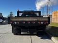 A 2011 Ford F-350 SD with a flatbed and multiple red and amber lights mounted on the back