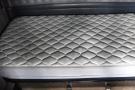 A grey mattress with a diamond pattern on a truck sleeper bed