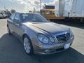 A silver 2007 Mercedes-Benz E-Class sedan with prominent headlights and a chrome grille showcasing the brand's logo on the front