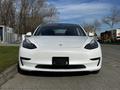 A white 2019 Tesla Model 3 viewed from the front showcasing its sleek design and distinctive headlights