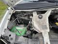 Open hood of a 2014 GMC Savana showing engine compartment with a green battery and various components including hoses and fluid reservoirs