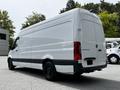 A 2023 Mercedes-Benz Sprinter van with a white body and black accents positioned at an angle showcasing its rear and side features